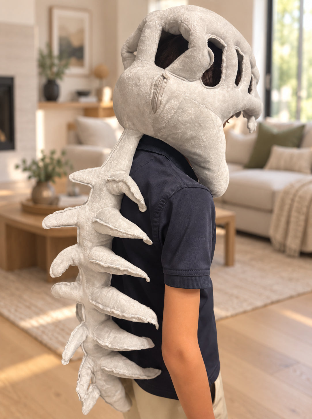 Person wearing the plush dinosaur skeleton costume while lying on a bed